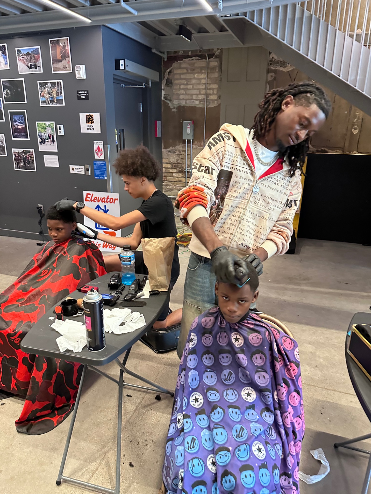 Multiple barbers providing free haircuts to youth at the Fresh and Fly Bash